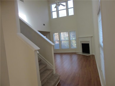 Unfurnished living room with stairs, dark wood-style flooring, a high ceiling, a fireplace, and a ceiling fan