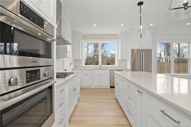 Expansive kitchen with Bosch suite of SS appliances, center island with Smoked Pearl Quartz tops, pendants, and walk in pantry.