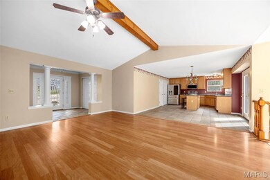 Unfurnished living room with light wood-style floors, decorative columns, a ceiling fan, and a chandelier