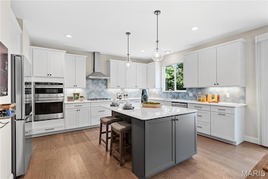 Kitchen with white cabinets, a breakfast bar, a kitchen island, light wood-style flooring, and light countertops