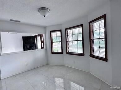 Empty room with tile patterned floors, baseboards, visible vents, and a textured ceiling