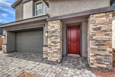 Entrance to property featuring stucco siding, a garage, and stone siding