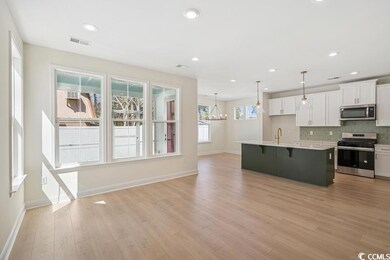 Kitchen featuring stainless steel appliances, white cabinets, a breakfast bar area, light countertops, and recessed lighting