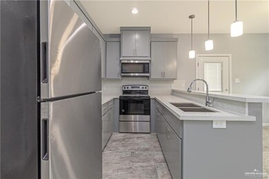 Kitchen featuring decorative light fixtures, gray cabinetry, stainless steel appliances, light tile floors, and sink