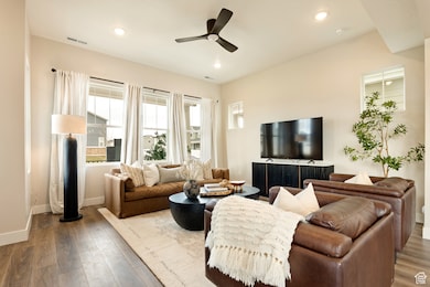 Living room with wood finished floors, a ceiling fan, and recessed lighting