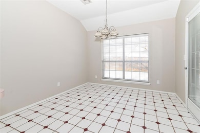 Empty room featuring a notable chandelier, vaulted ceiling, and a wealth of natural light