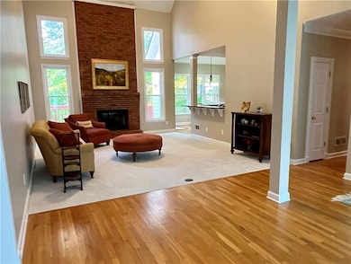 Living area with a towering ceiling, light wood-style flooring, a fireplace, light colored carpet, and ornate columns