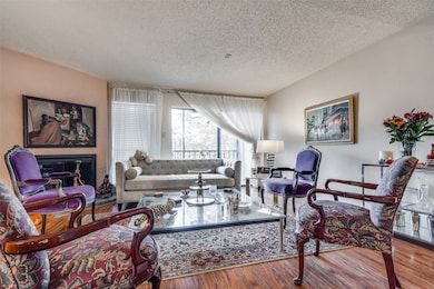 Living room featuring a textured ceiling, a glass covered fireplace, and wood finished floors