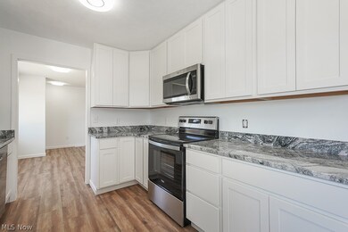 Kitchen featuring appliances with stainless steel finishes, light wood-type flooring, and white cabinetry