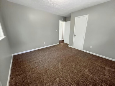 Unfurnished bedroom featuring dark carpet, baseboa