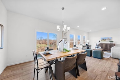 Dining area with light wood finished floors, recessed lighting, and a chandelier
