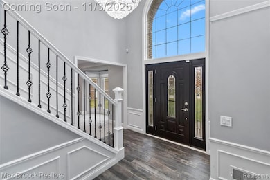 Entryway with a decorative wall, a wainscoted wall, a towering ceiling, a chandelier, and dark wood finished floors