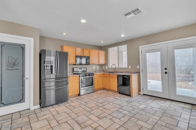 Kitchen featuring black appliances, light brown cabinets, french doors, and recessed lighting