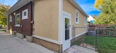 View of side of home featuring stucco siding and a gate