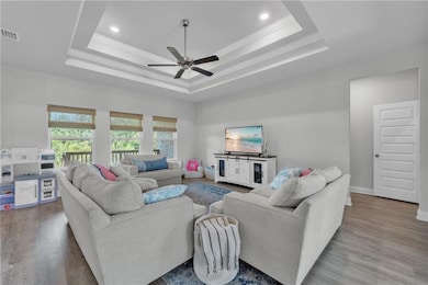 Living room with a tray ceiling, ornamental molding, a ceiling fan