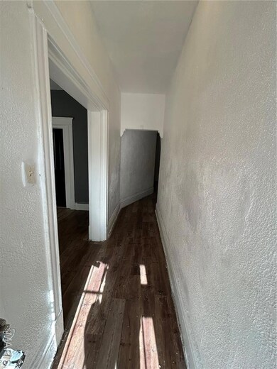 Hall with a textured wall and dark wood-style floors
