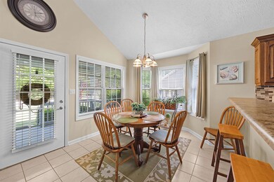 Dining room with an inviting chandelier, baseboards, light tile patterned flooring, and lofted ceiling