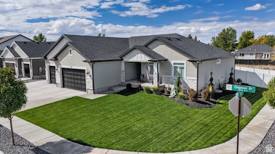View of front of home with stucco siding, stone siding, a garage, driveway, and roof with shingles