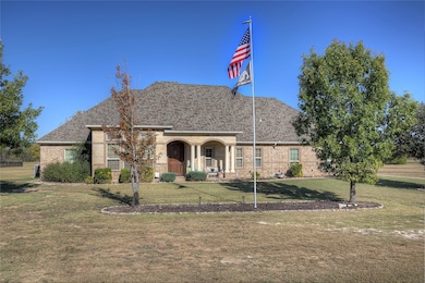 View of front facade featuring brick, covered porch, a front lawn, and composition shingles.
