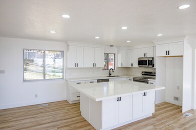 Kitchen with stainless steel appliances, white cabinets, recessed lighting, a kitchen island, and light wood-type flooring