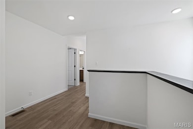 Hallway with wood finished floors and recessed lighting