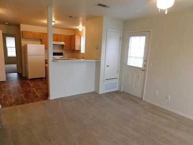 Kitchen featuring freestanding refrigerator, dark colored carpet, light countertops, and a peninsula
