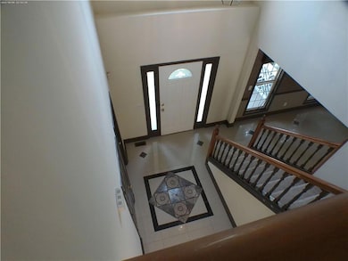 Tiled entryway with inlaid floor details, baseboards, and a towering ceiling