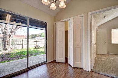 Unfurnished bedroom with lofted ceiling, a textured ceiling, multiple windows, wood finished floors, and a chandelier