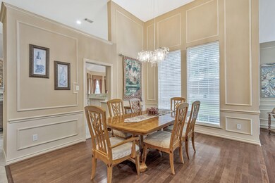 Dining room with a healthy amount of sunlight, a towering ceiling, a notable chandelier, and dark hardwood / wood-style flooring