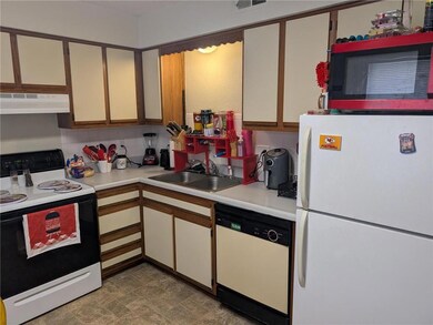 Kitchen with white appliances, under cabinet range hood, light countertops, and tasteful backsplash