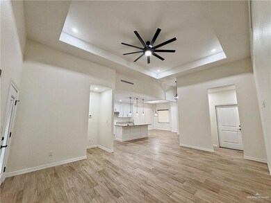 Unfurnished living room featuring ceiling fan, light wood-type flooring, a raised ceiling, baseboards, and recessed lighting