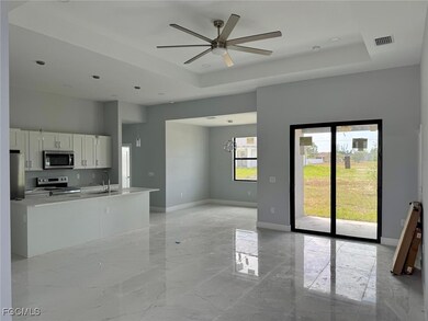 Kitchen with light marble finish floors, a raised ceiling, white cabinets, stainless steel appliances, and open floor plan
