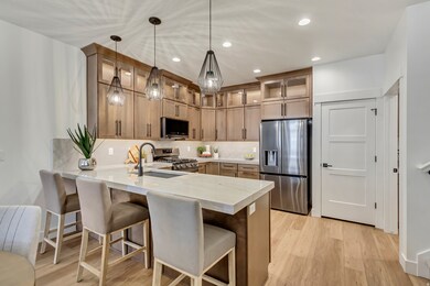 Kitchen with a kitchen bar, stainless steel appliances, a peninsula, light wood finished floors, and recessed lighting