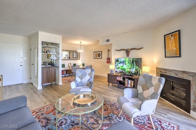 Living room with light wood-type flooring, a textured ceiling, and a fireplace