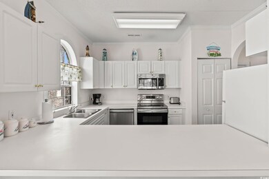 Kitchen with white cabinets, appliances with stain