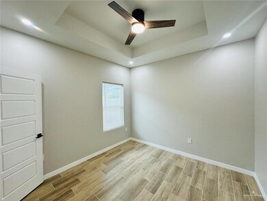 Spare room with a tray ceiling, baseboards, a ceiling fan, and wood finish floors