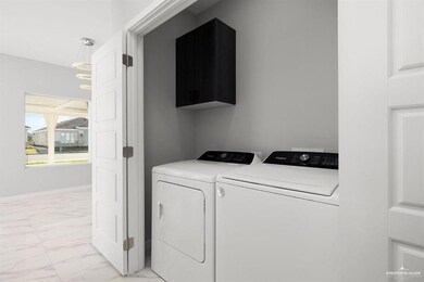 Laundry room featuring washing machine and dryer, light marble finish flooring, and cabinet space