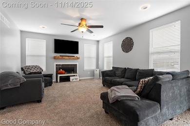 Living area featuring carpet floors, ceiling fan, and a fireplace