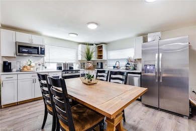 Kitchen with stainless steel appliances, light countertops, white cabinetry, and light wood-type flooring