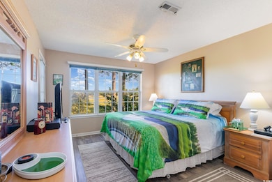 Bedroom with ceiling fan, a textured ceiling, and 