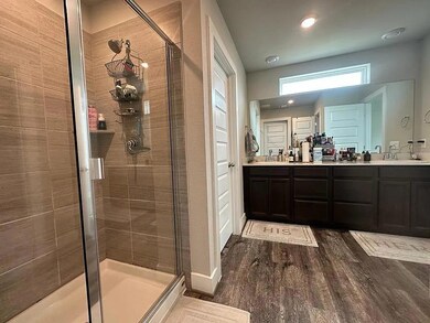 Bathroom featuring a stall shower, double vanity,