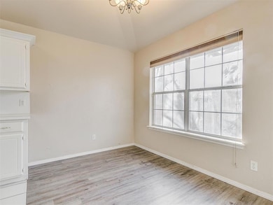 Spare room featuring light wood finished floors, a chandelier, baseboards, and lofted ceiling