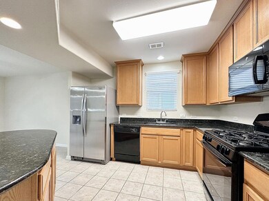 Kitchen with black appliances, light tile pattern