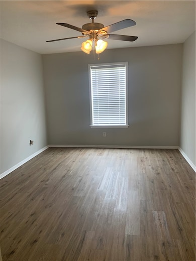 Spare room featuring baseboards, dark wood finishe