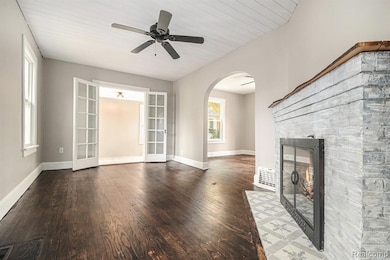 Unfurnished living room with arched walkways, dark wood finished floors, french doors, a fireplace, and wooden ceiling