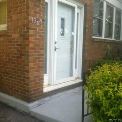Front entry at concrete stoop leads to foyer and l