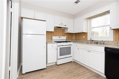 Kitchen with a sink, visible vents, white cabinetr