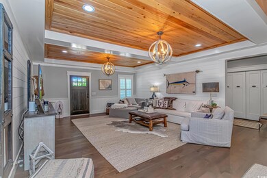 Living room with a tray ceiling, a chandelier, wood ceiling, dark wood-style floors, and recessed lighting