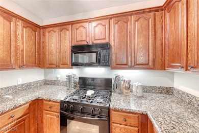 Kitchen with black appliances, light stone counter