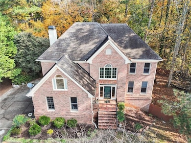 View of front of house featuring a chimney, brick siding, and roof with shingles